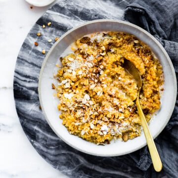 Overhead view stone bowl filled with serving of creamy vegan pumpkin quinoa breakfast.