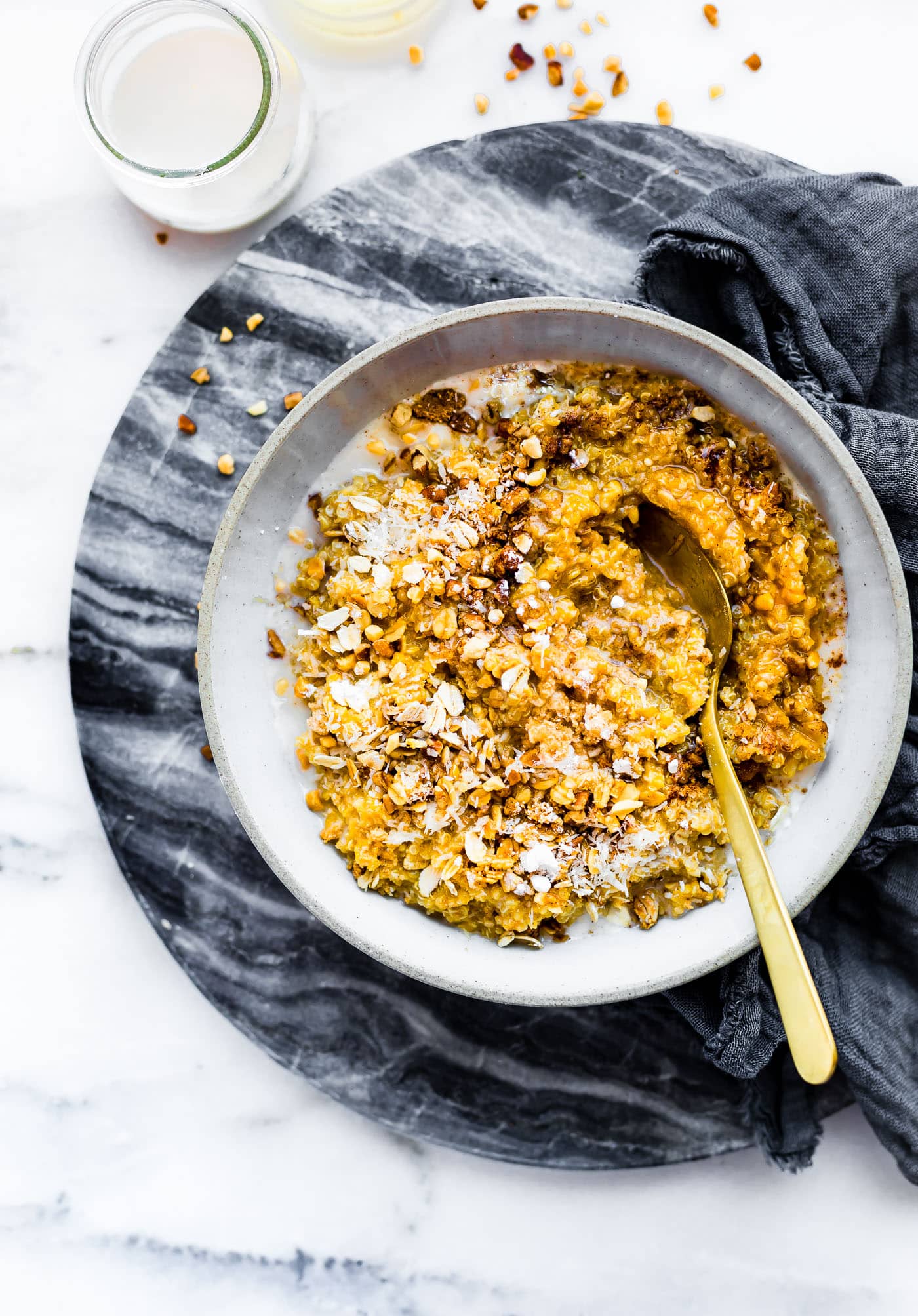 Creamy Pumpkin Quinoa breakfast in stone bowl with gold spoon.