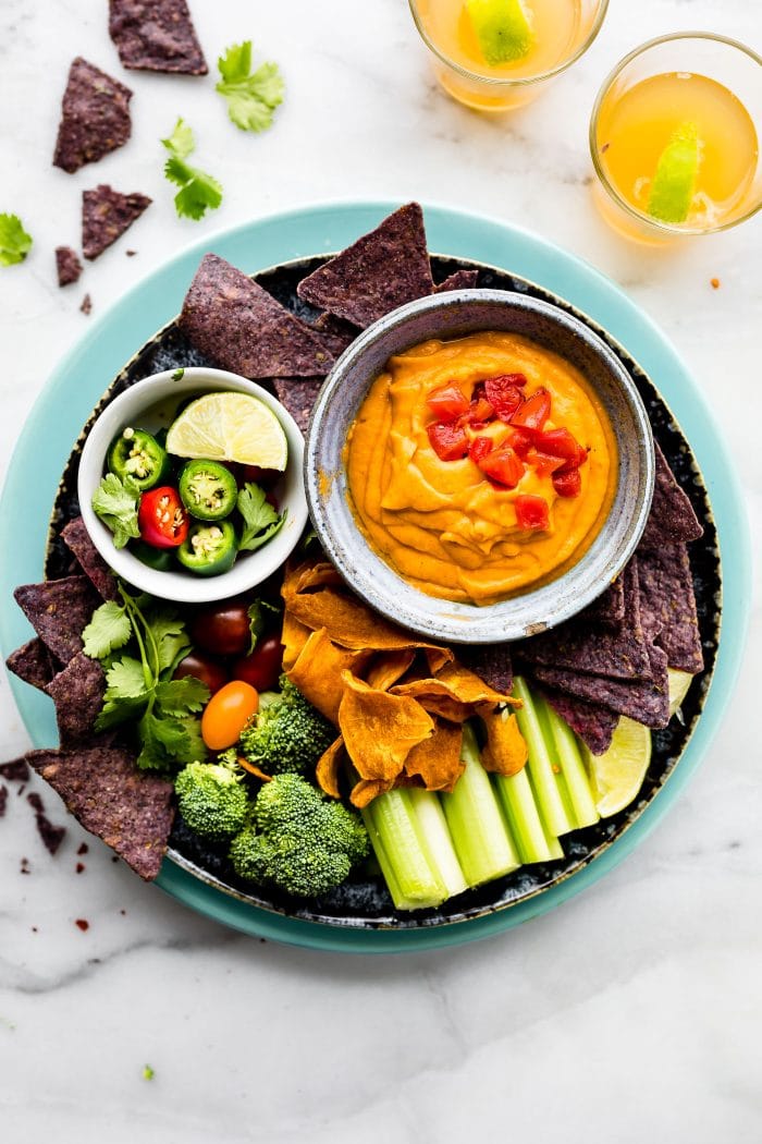 vegan salsa con queso with raw veggies for dipping on blue tray.