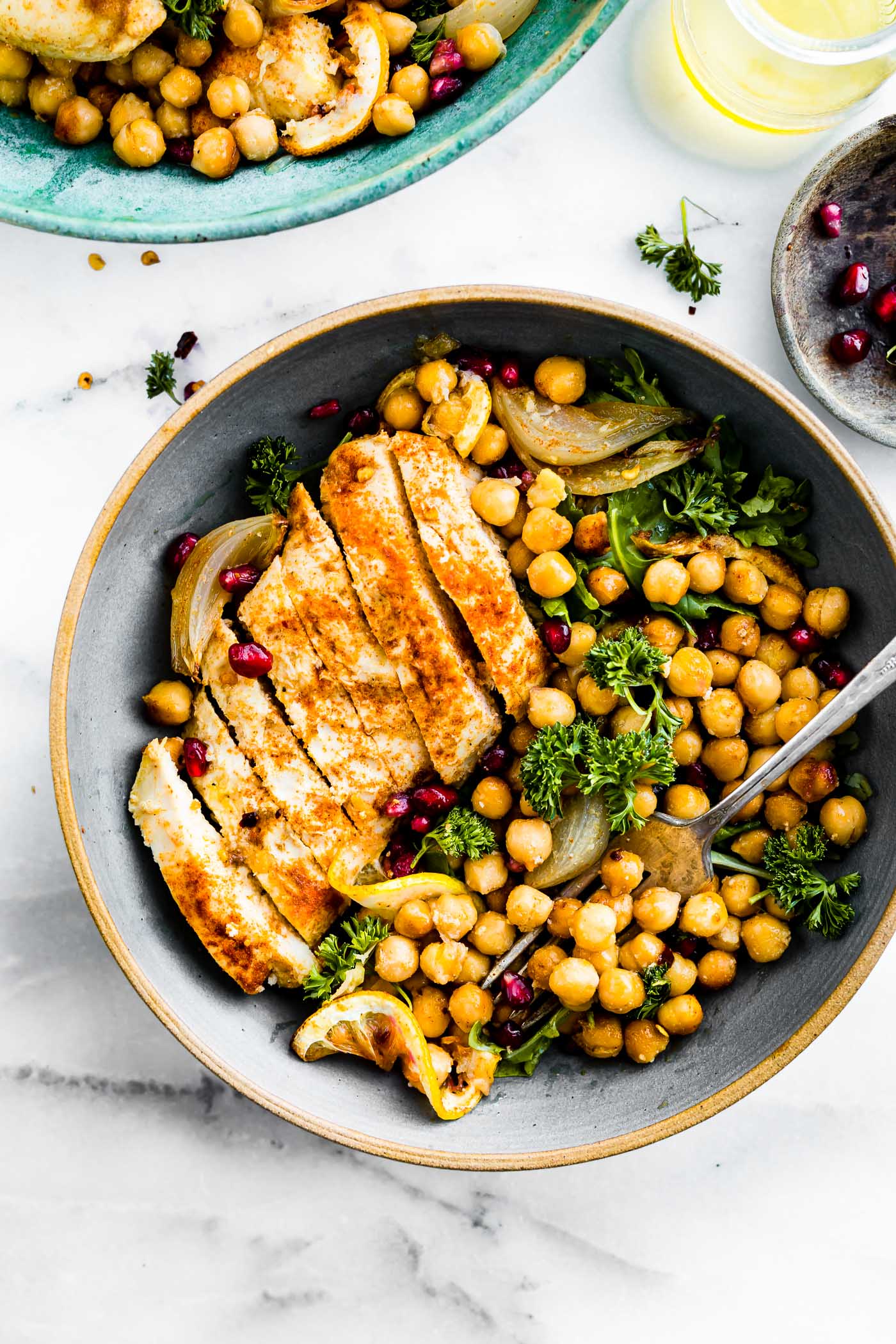 Cumin roasted chicken, sliced in turquoise bowl with roasted chickpeas and greens.