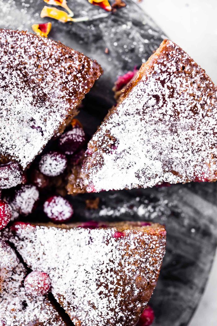 Close up view slices of cranberry sour cream almond cake sprinkled with powdered sugar