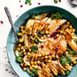 Overhead view cumin roasted chickpea chicken, cut in strips in turquoise bowl with chickpeas and greens.