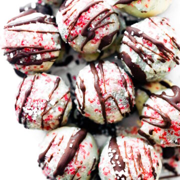 Overhead view White Chocolate Peppermint Rum Balls drizzled with dark chocolate and sprinkled with red sugar crystals.