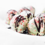 Side view several white chocolate coated peppermint rum balls with red sprinkles