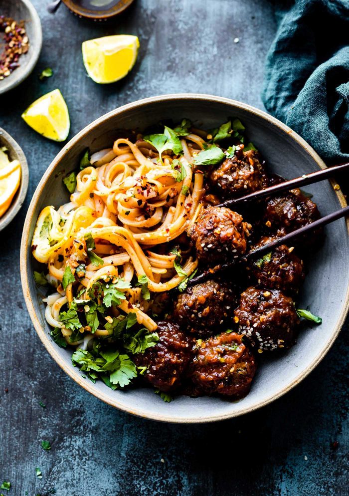 5-spice BBQ meatballs served in bowl with noodles, chopsticks picking up meatball