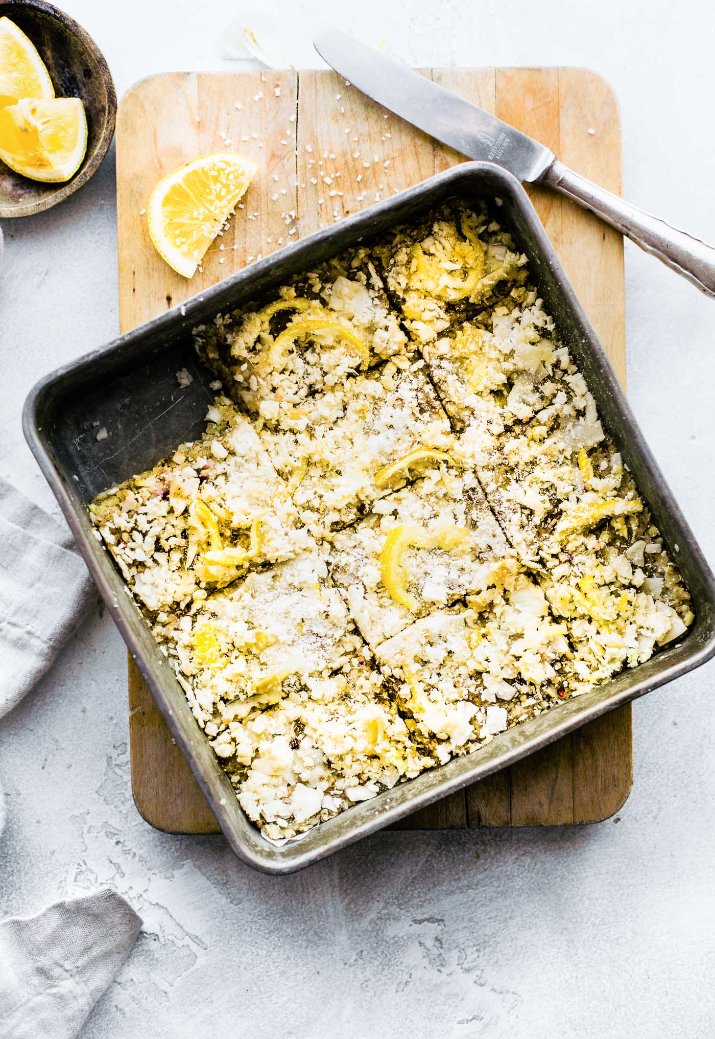 Overhead view square baking pan filled with lemon coconut energy bars, one bar removed from pan