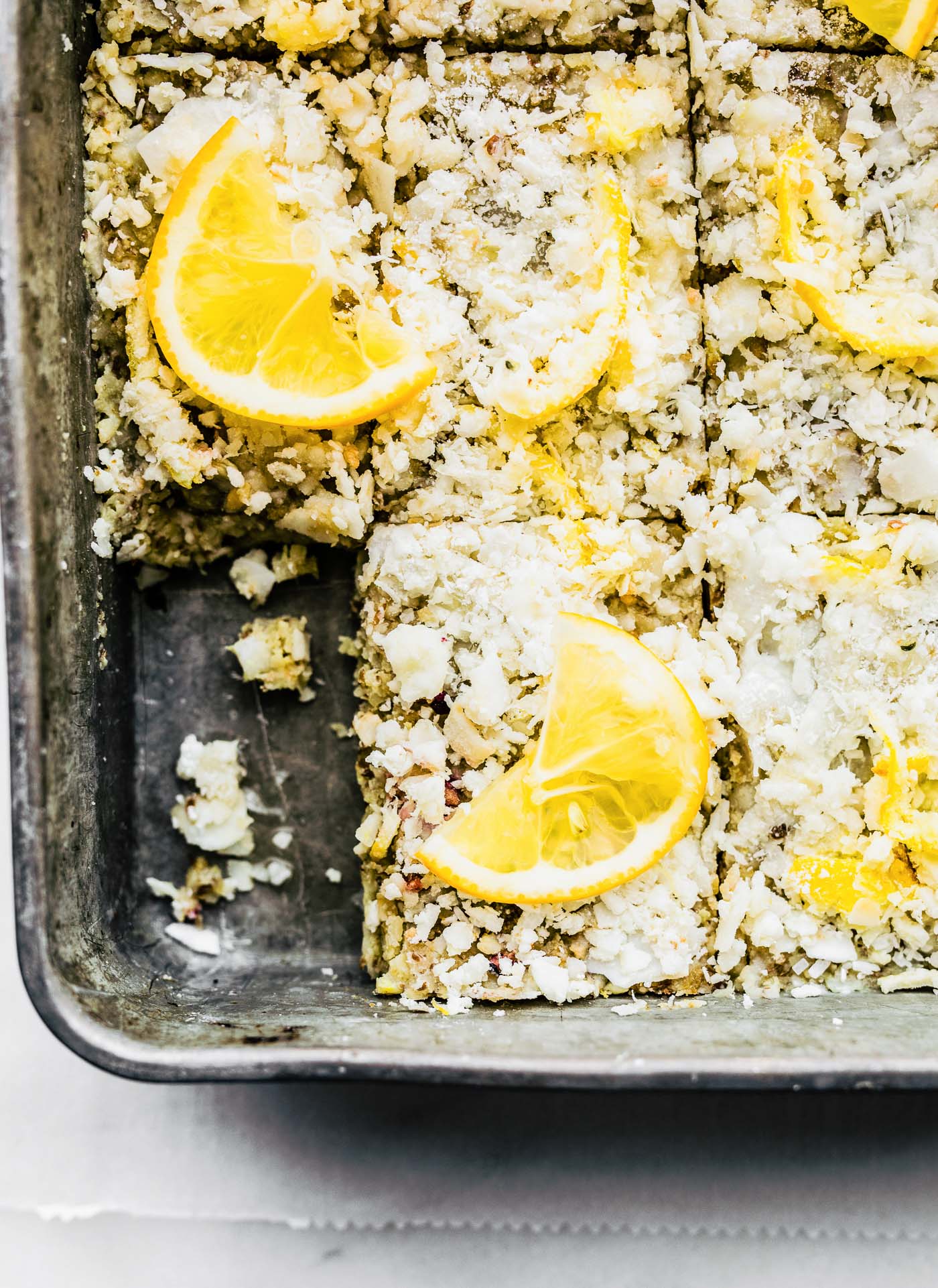 Close up overhead view lemon coconut energy bars cut into rectangles in baking pan.
