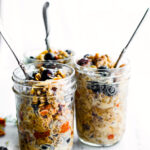 superood instatn pot oatmeal in mason jars topped with berries and served with spoons sticking out of the top.