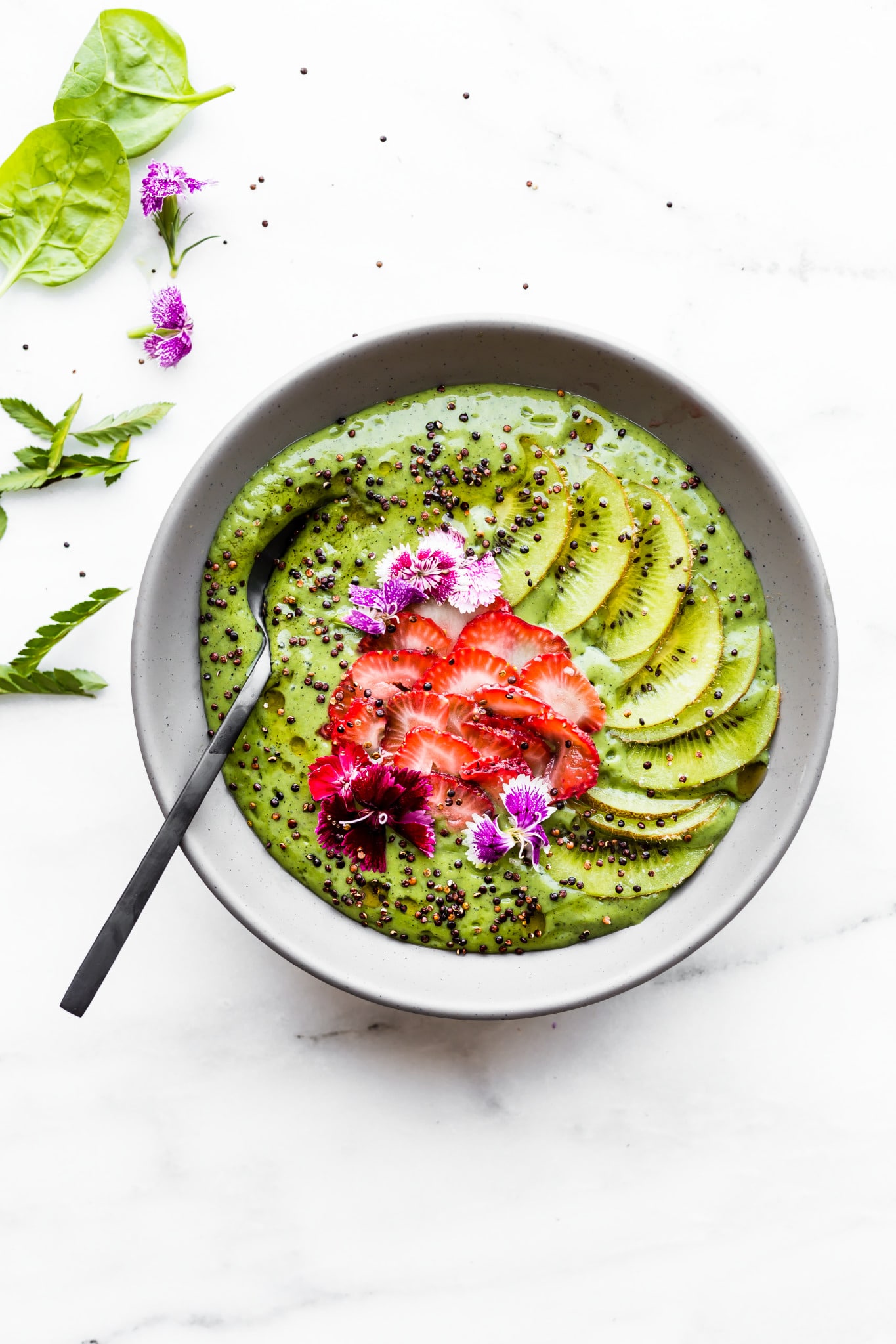 Overhead image of green smoothie bowl with kiwi, strawberries, and chia seeds.