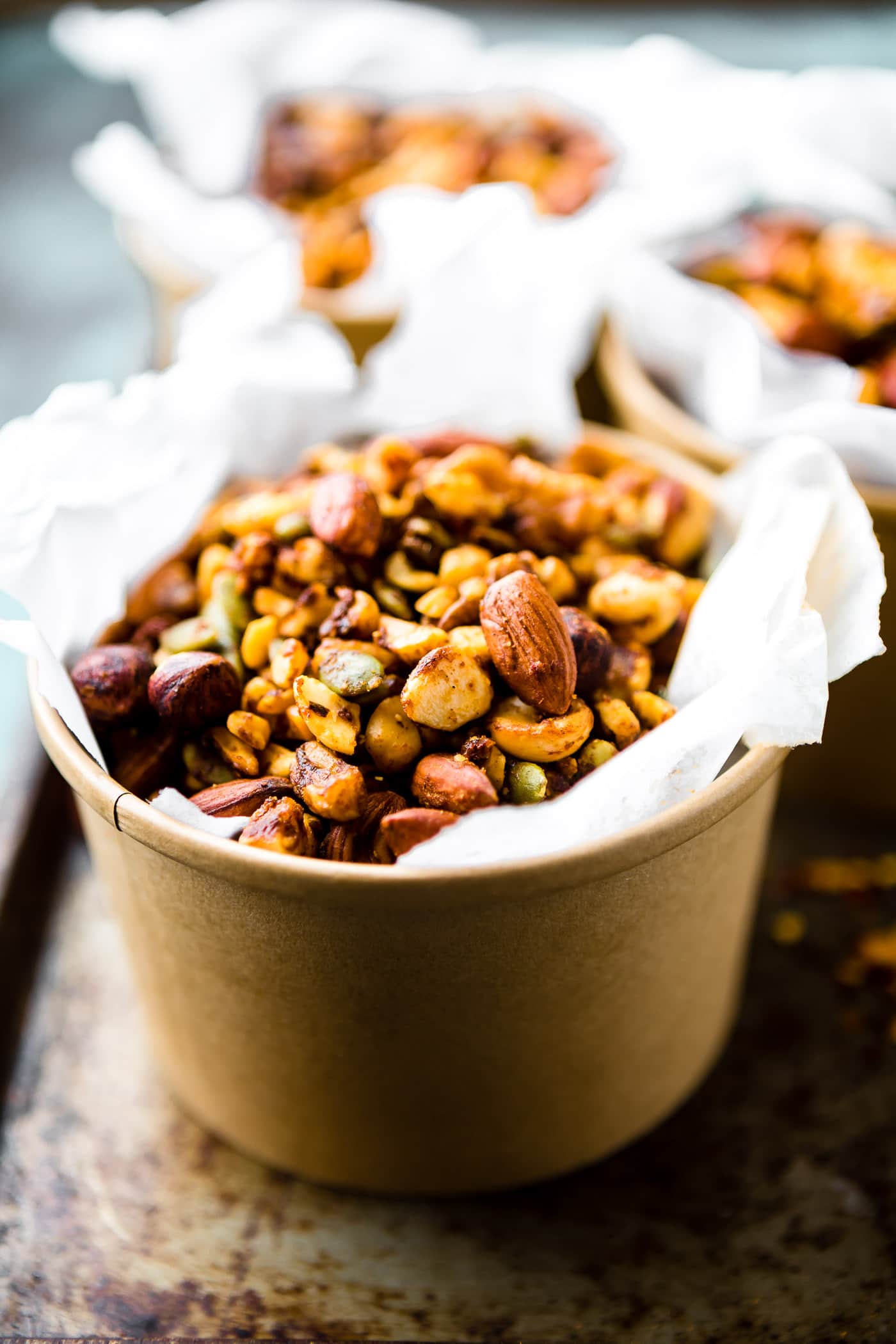 Curry spiced slow cooker trail mix in parchment-lined brown paper bowls.