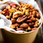 Close up overhead view slow cooker curry snack mix in brown paper bowl
