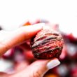 woman holding a fudgy strawberry chocolate brownie ball in her fingers