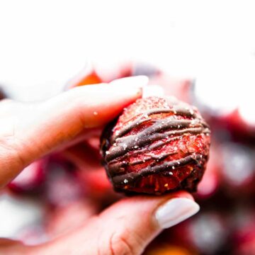 woman holding a fudgy strawberry chocolate brownie ball in her fingers