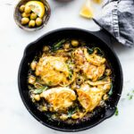 Overhead view cast iron skillet filled with baked chicken thighs with lemon sage marinade