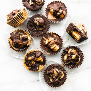 Several caramelized banana chocolate almond butter cups topped with chocolate shavings and sea salts arranged together.