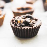 caramelized banana vegan almond butter cups lined up with silver backdrop