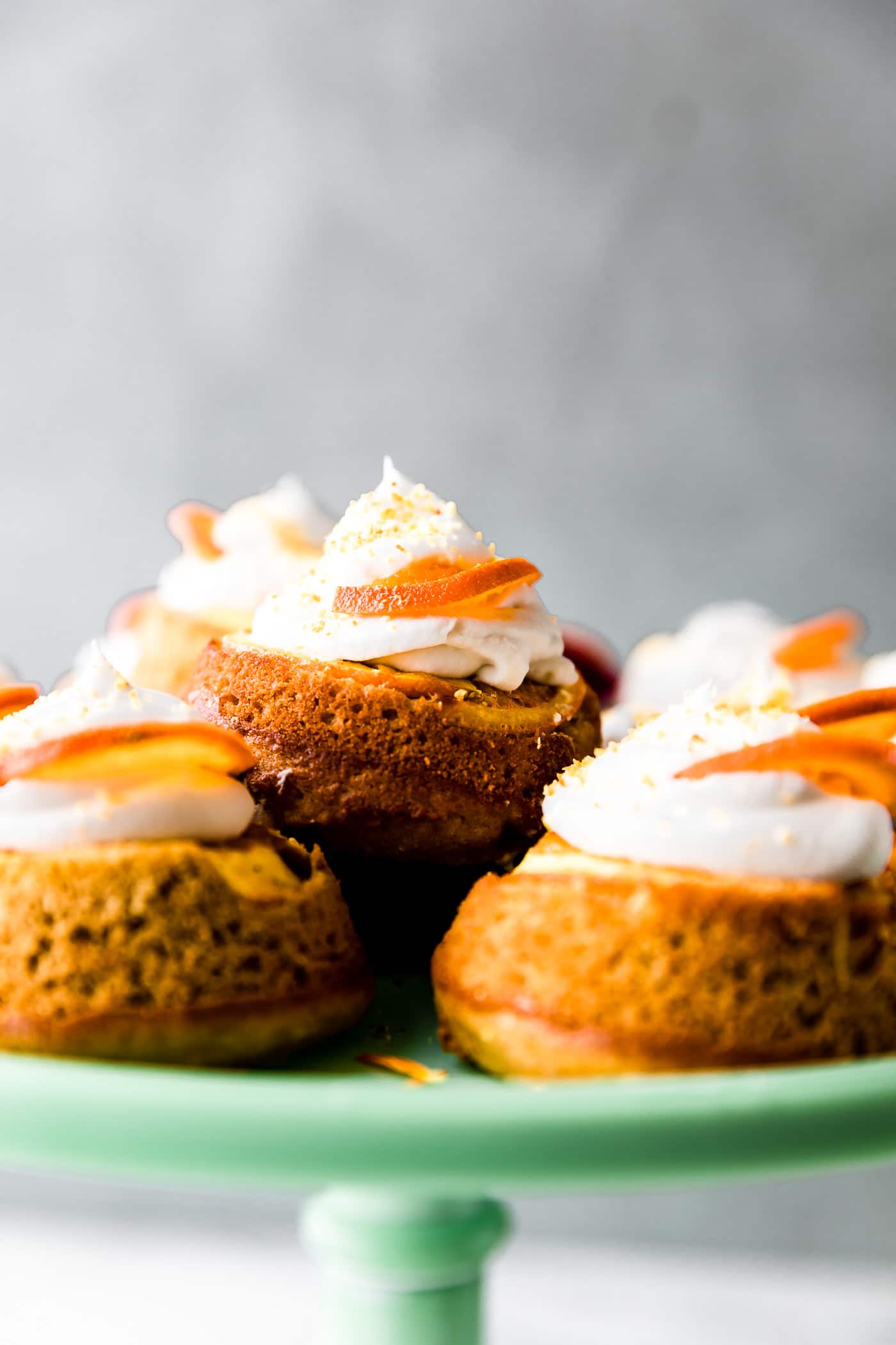 Mini upside down cakes with whipped cream and orange slices.