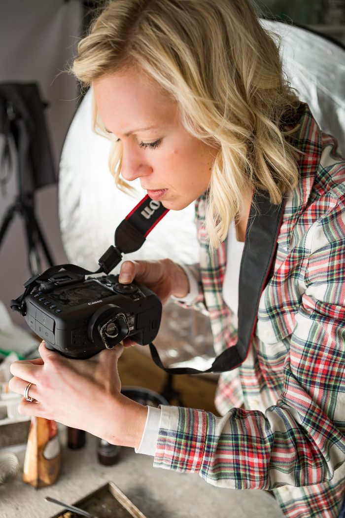 A woman with blonde hair positioning dslr camera over food to take photos