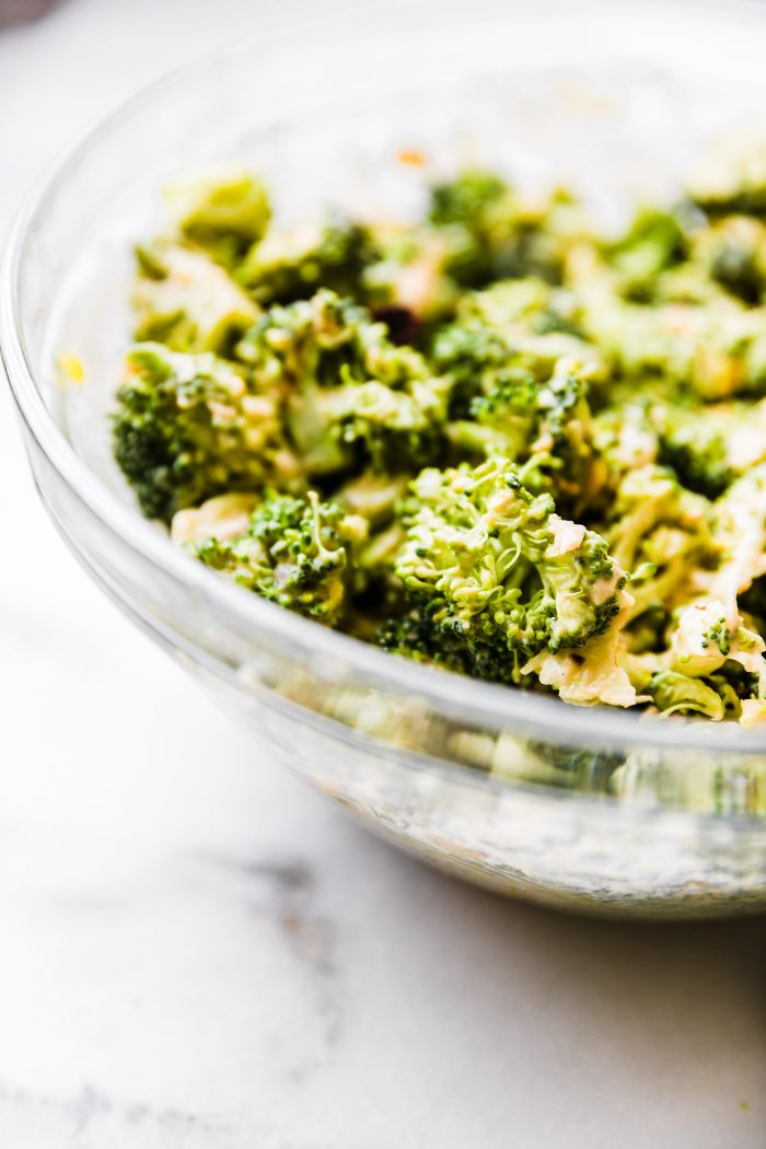broccoli florets in glass bowl mixed with yogurt sauce.