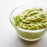 Clear glass bowl filled with dill pesto sauce.