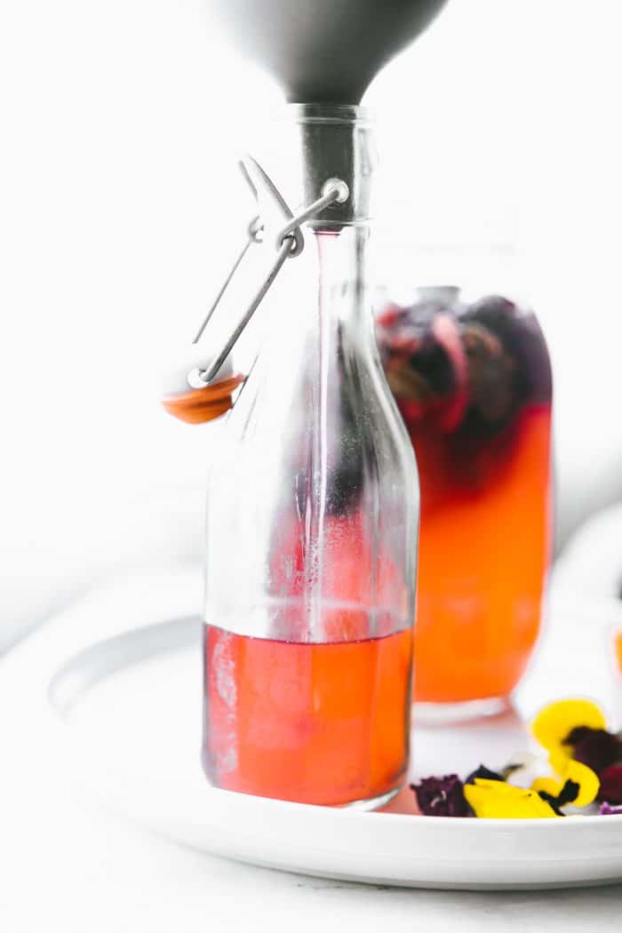 orange probiotic drink being bottled through a funnel.