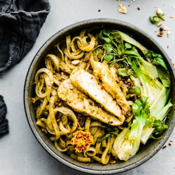 Overhead view Asian pesto chicken noodle stir fry in stone bowl.