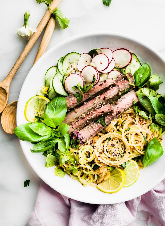 Spiralized Apple Kimchi Salad with Beef in white bowl with chopsticks on the side.