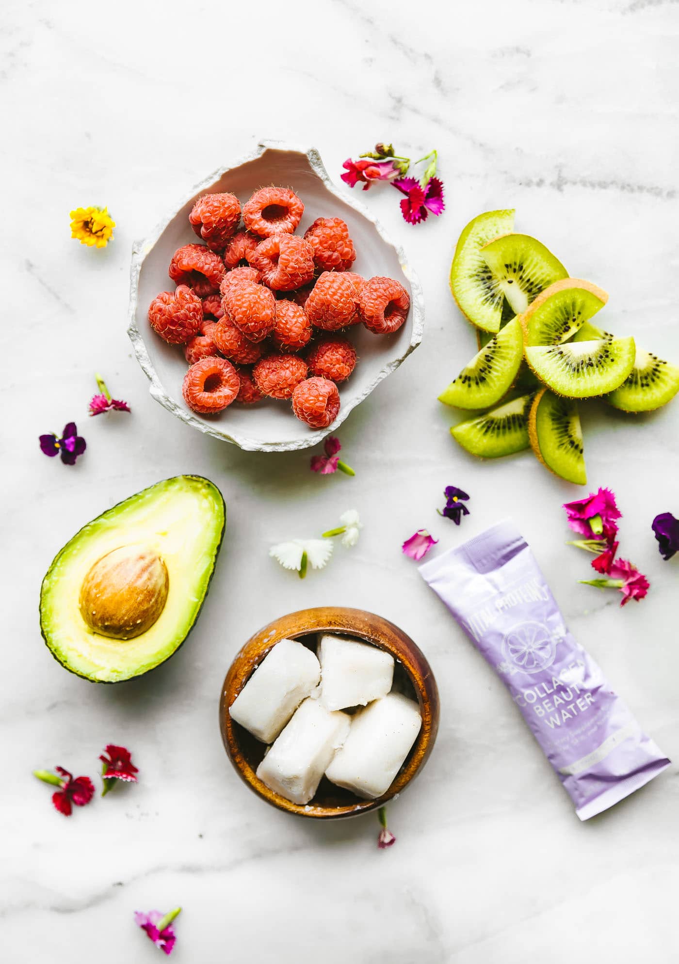 Ingredients for raspberry, kiwi, avocado smoothie arranged together on counter.