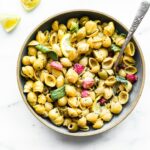 chickpea pasta with lemon herb sauce and roasted radish in serving bowl with serving spoon.