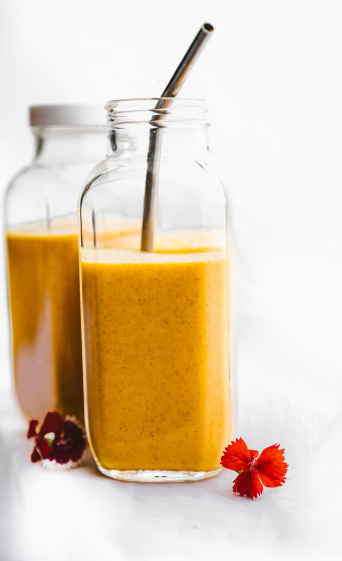 probiotic immunity boosting orange smoothies in two tall glass jars, one with straw in smoothie