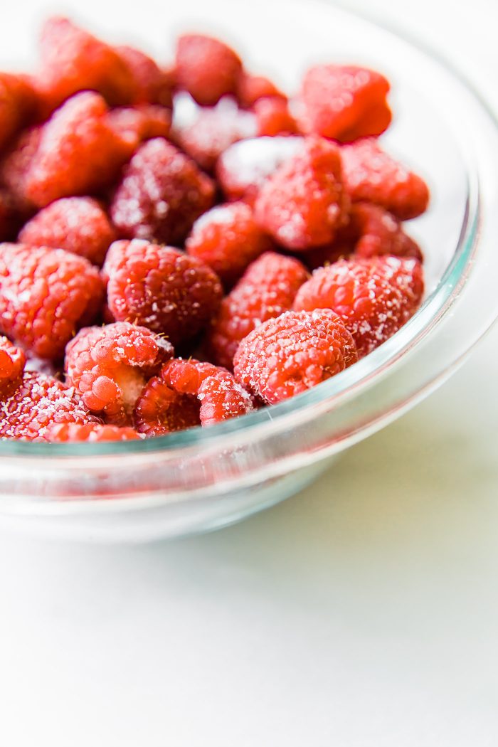 Macro view fresh raspberries in clear glass bowl.