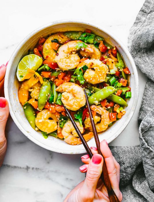 wok fired orange garlic shrimp stir fry recipe! It's full of fresh, snappy Asian flavors and made all in one pan! Shrimp, bell peppers, and snap peas are coated in a delicious spicy honey orange sauce.  Gluten free, Whole 30 friendly, and can be adapted for a paleo version. #stirfry #asian #healthy #onepan #lowcarb #paleo