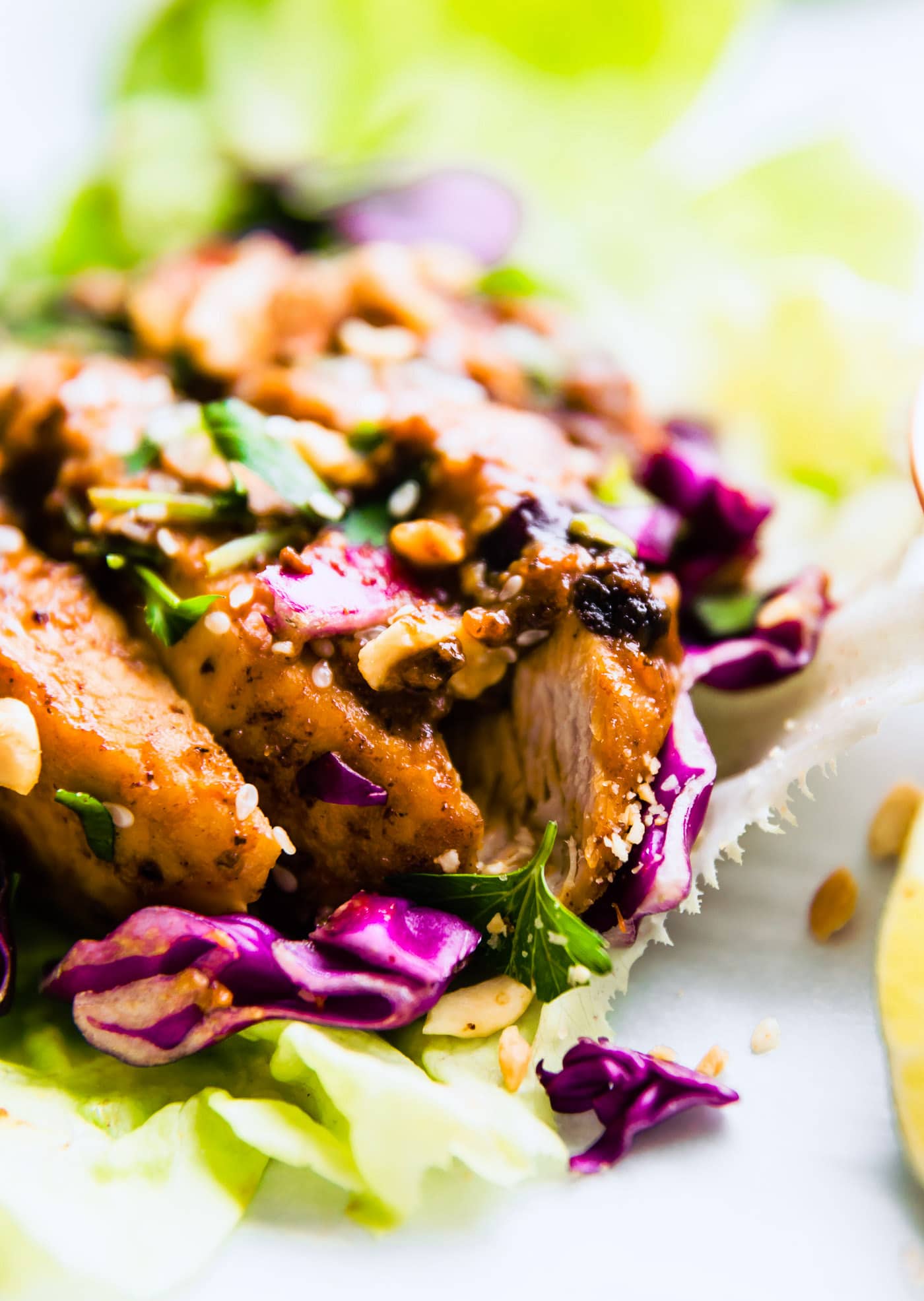 Close up side view Sticky Chinese BBQ Pork Lettuce Wraps topped with sauce and shredded purple cabbage