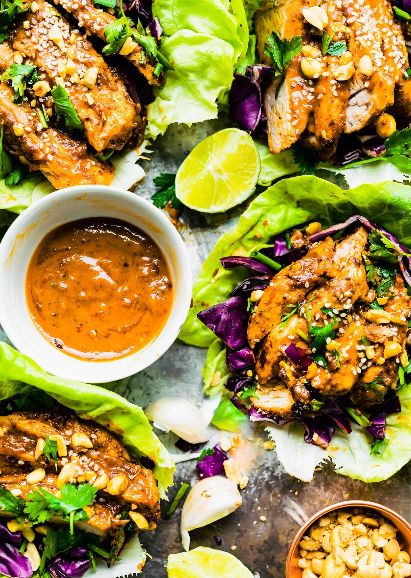 Sticky Chinese BBQ Pork Lettuce Wraps topped with sesame seeds, bowl of sauce in middle of lettuce wraps.