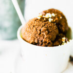 Double scoop espresso dark chocolate sorbet in white paper cup with white spoon.