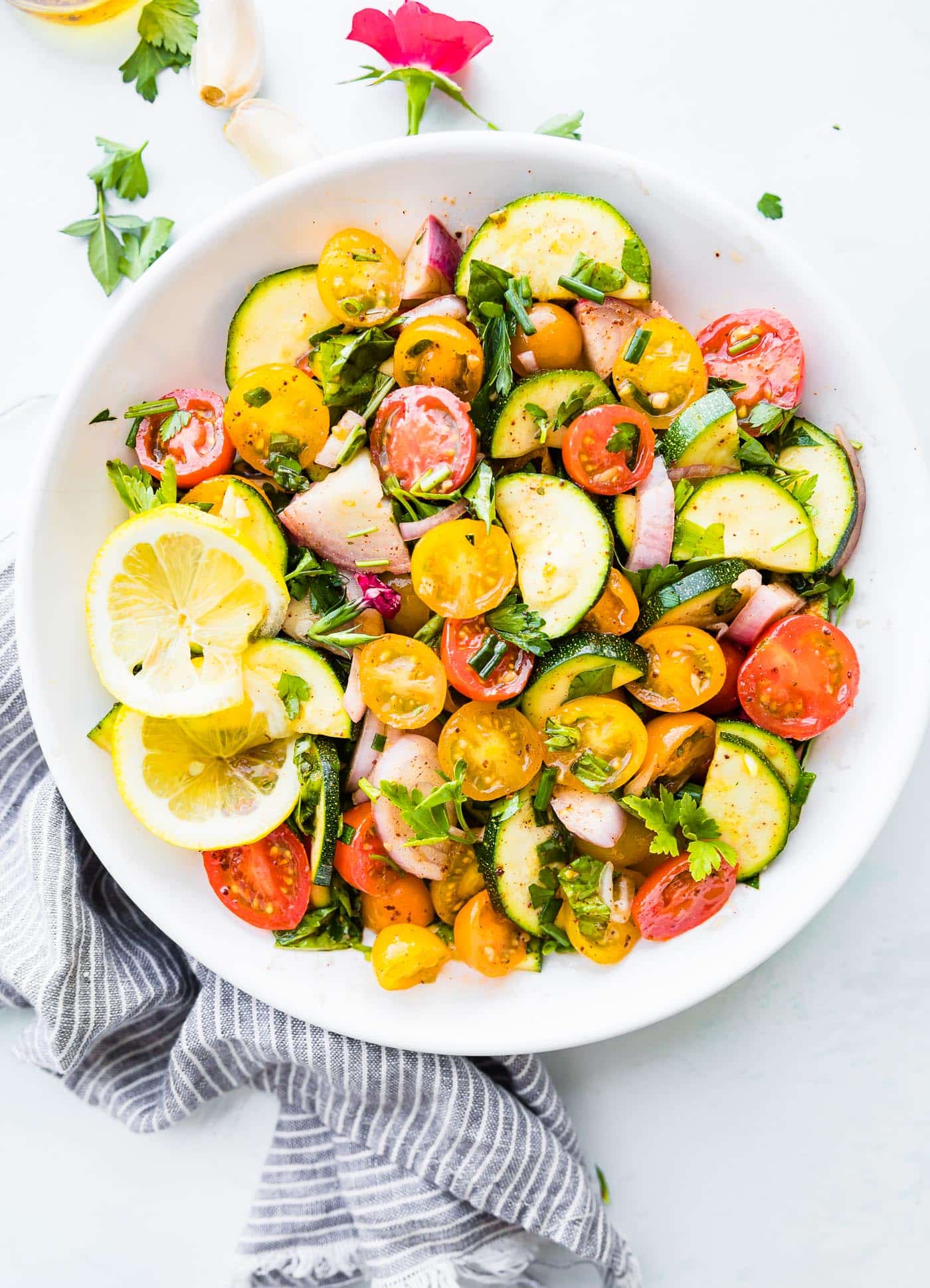 healthy marinated vegetables salad with tomatoes and zucchini in white bowl.