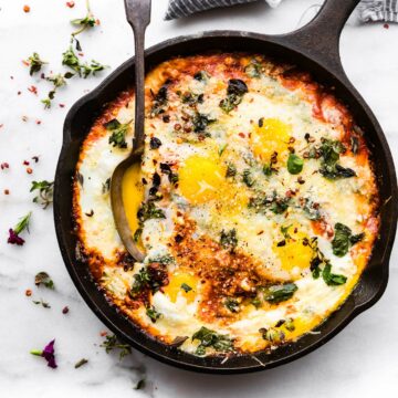 italian egg bake in cast iron skillet topped with fresh herbs.