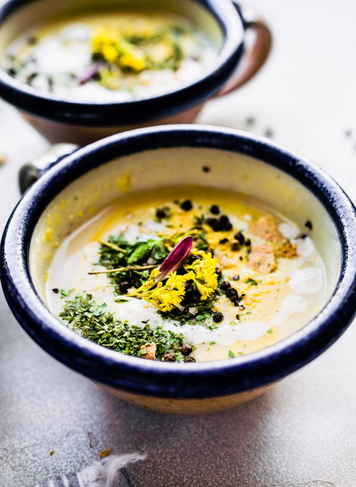 a bowl of roasted cauliflower soup topped with fresh herbs