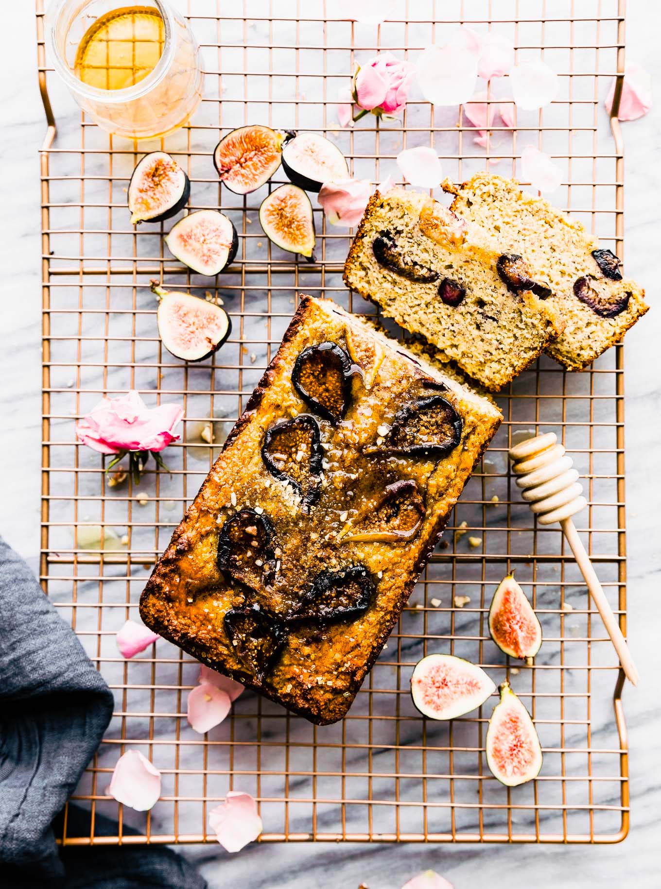 Almond flour loaf cake with honey roasted figs baked into top, on cutting board with two thick slices cut from loaf.