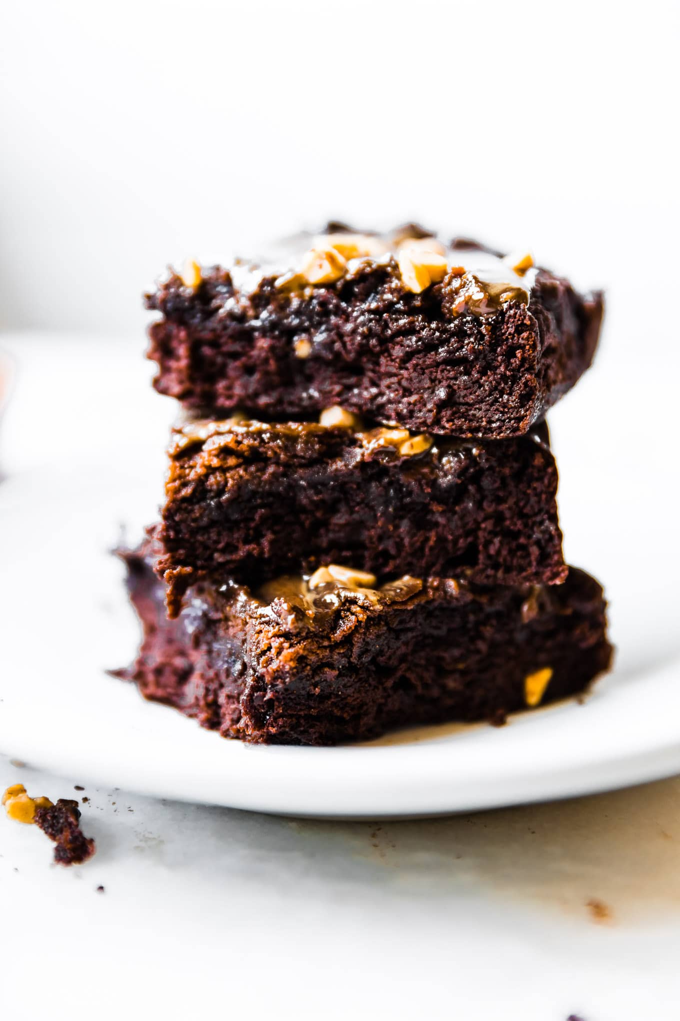 Stack of maple tahini brownies topped with nuts stacked up on each other.