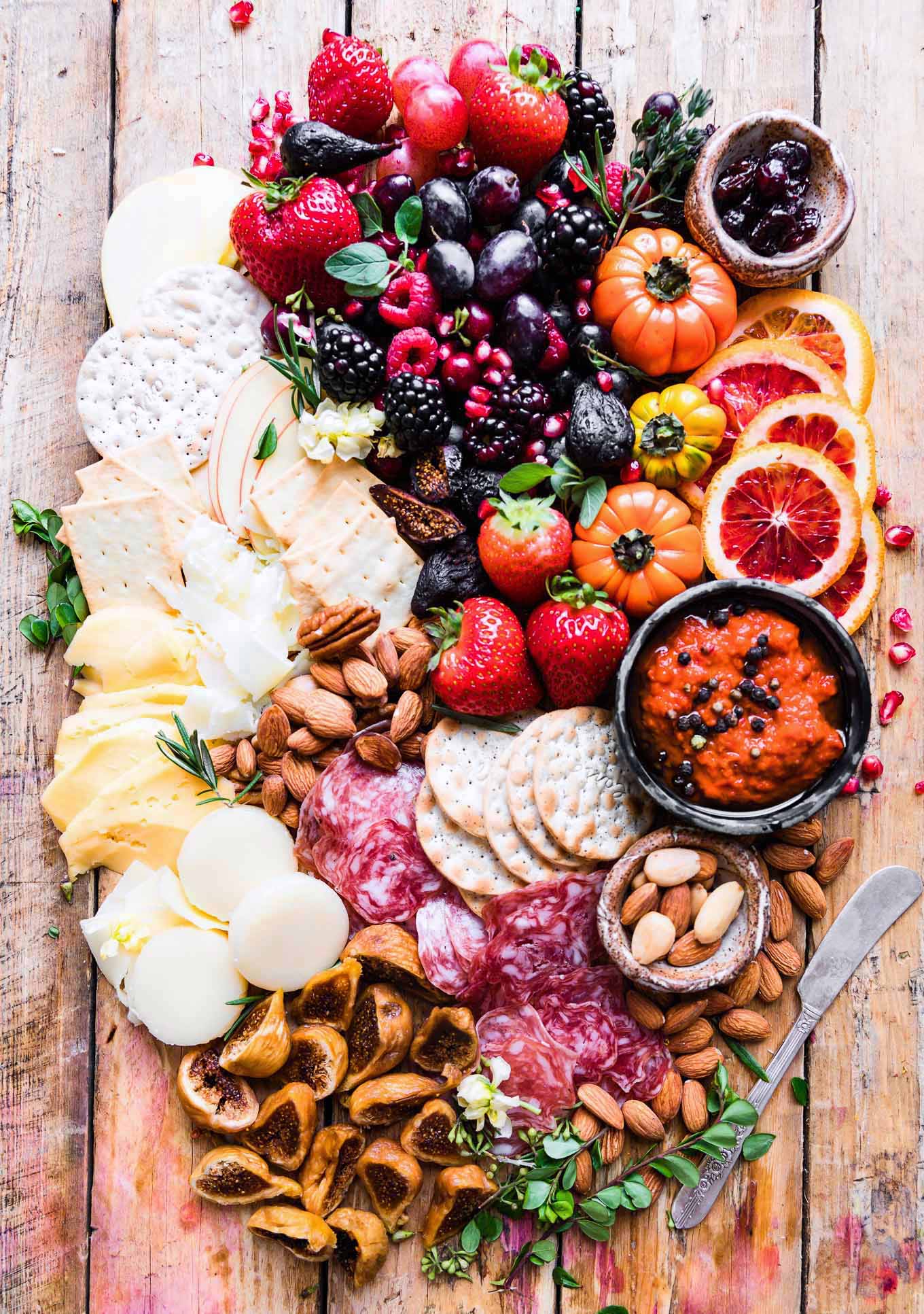 Festive Easy cheese board platter with berries, cheese, crackers, dried meat, nuts, dip, figs, and berries
