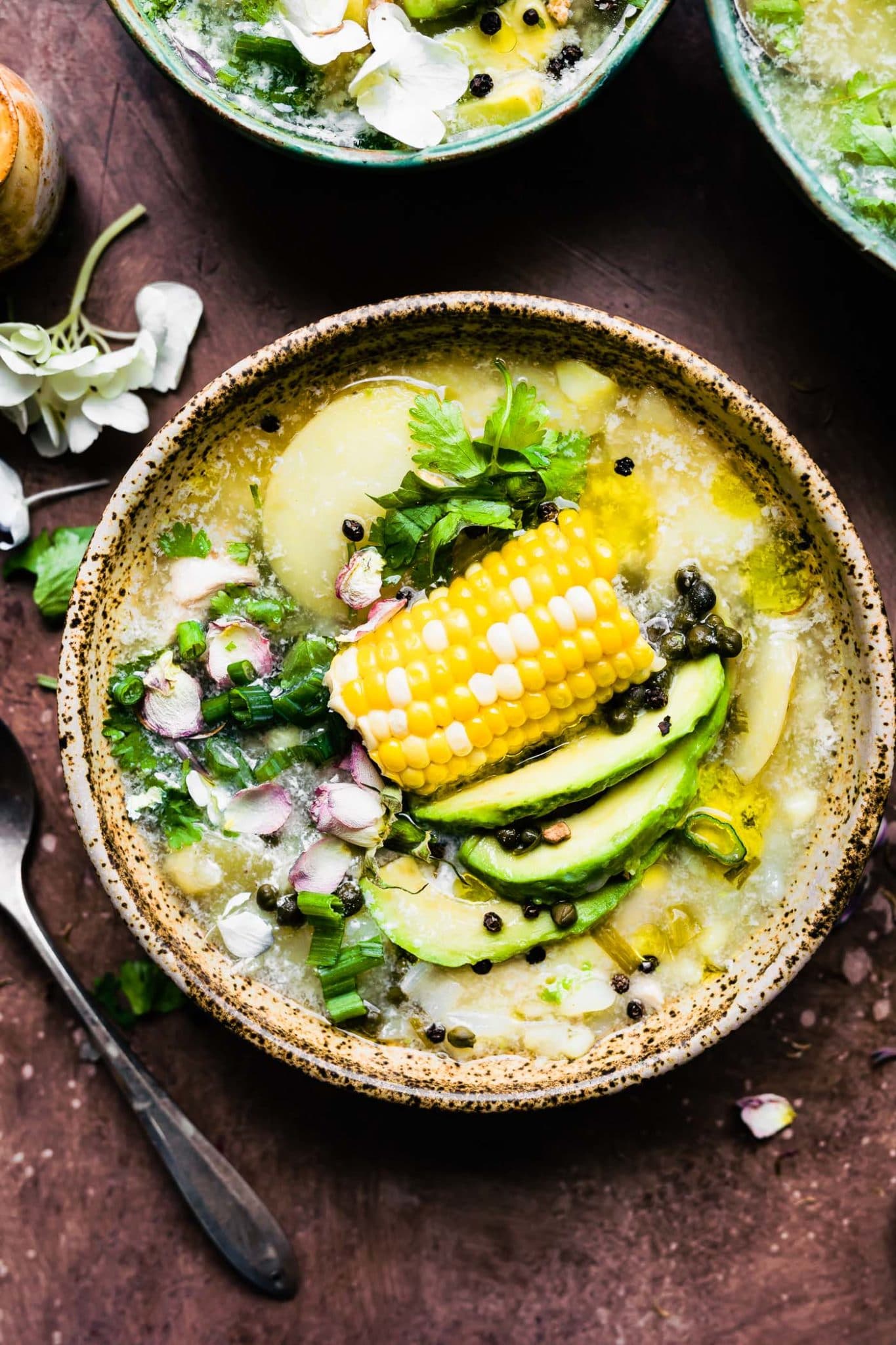 Instant pot chicken and potato soup with corn on the cob, avocado slices, scallions, and cilantro