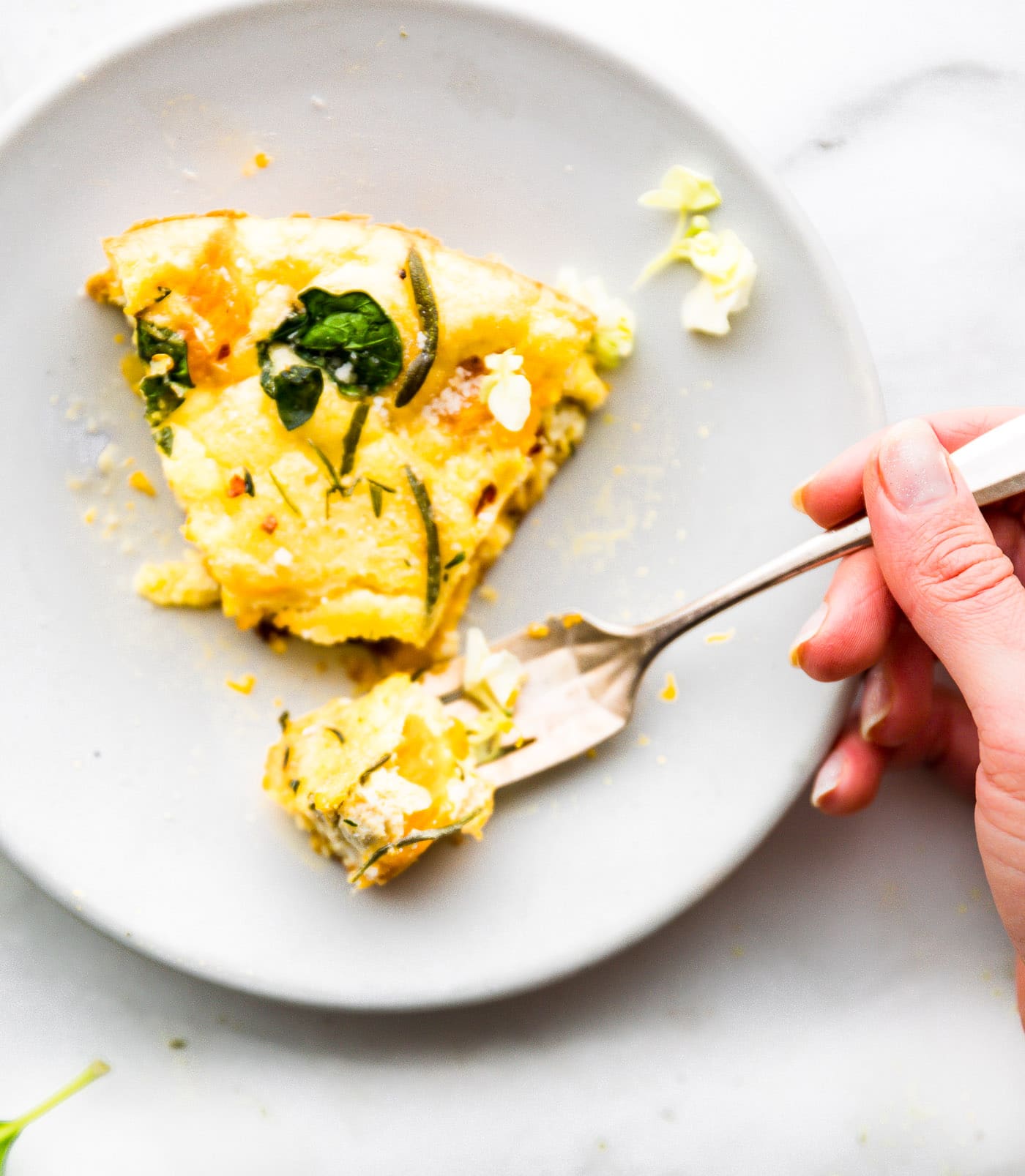 A fork full of pumpkin frittata from a slice of frittata on a white plate.