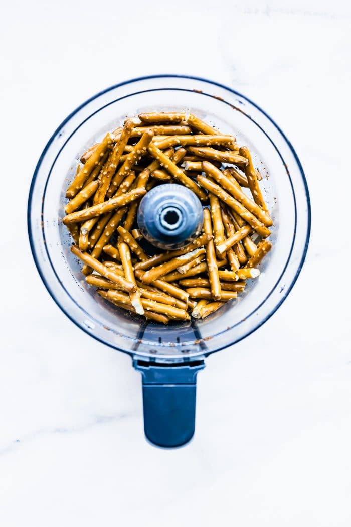 Overhead view food processor bowl with pretzel sticks in it.