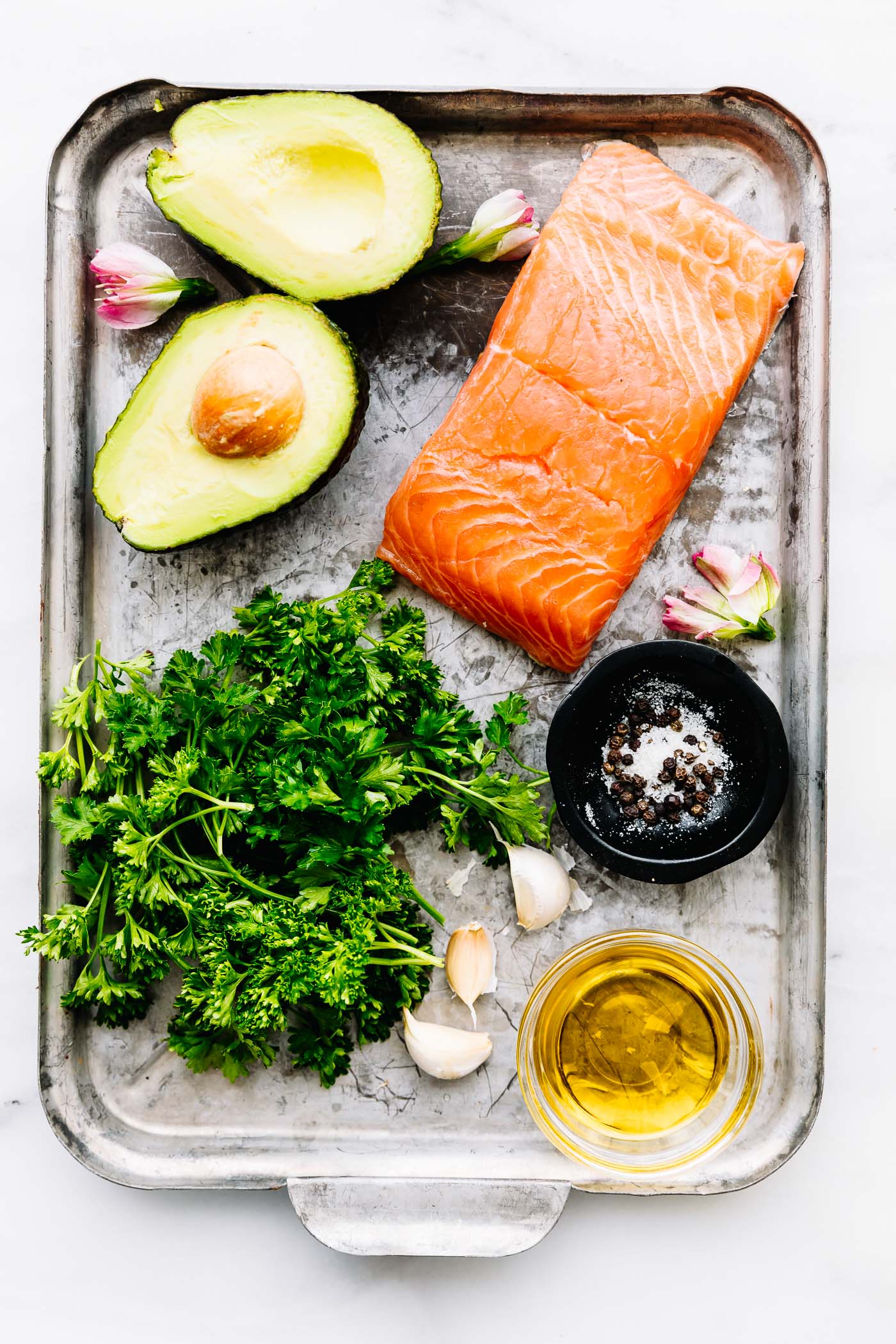 All ingredients for pan seared salmon with avocado gremolata in a silver baking pan.
