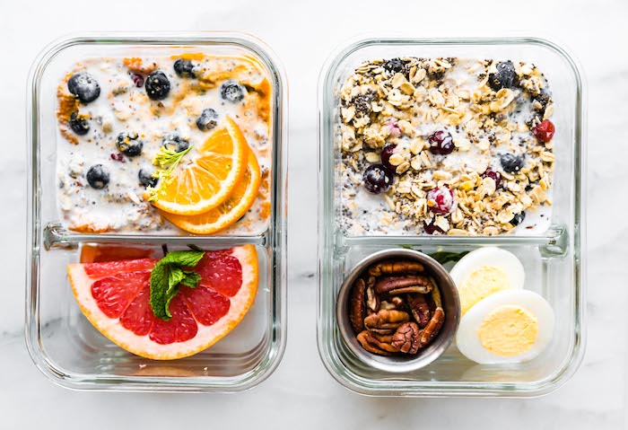 Two meal prep containers filled with overnight oats, fruit, hard boiled eggs, and nuts.