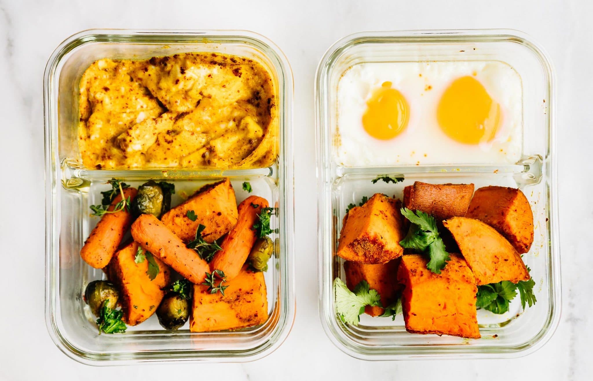 Two meal prep containers filled with eggs, curry chicken, and roasted sweet potatoes.