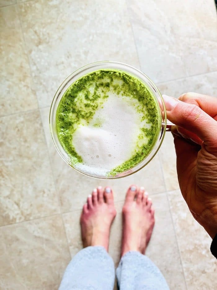 A hand holding a cup of matcha latte