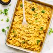 Sheet pan filled with turmeric scrambled eggs, a wooden spoon in the eggs.