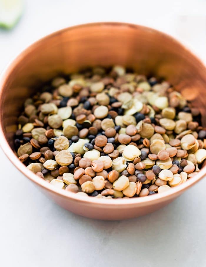 A mixture of colored lentils in a small brown bowl.